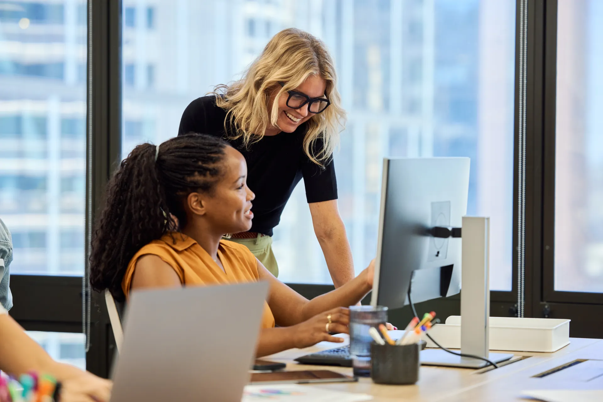 two female office workers talking at the computer