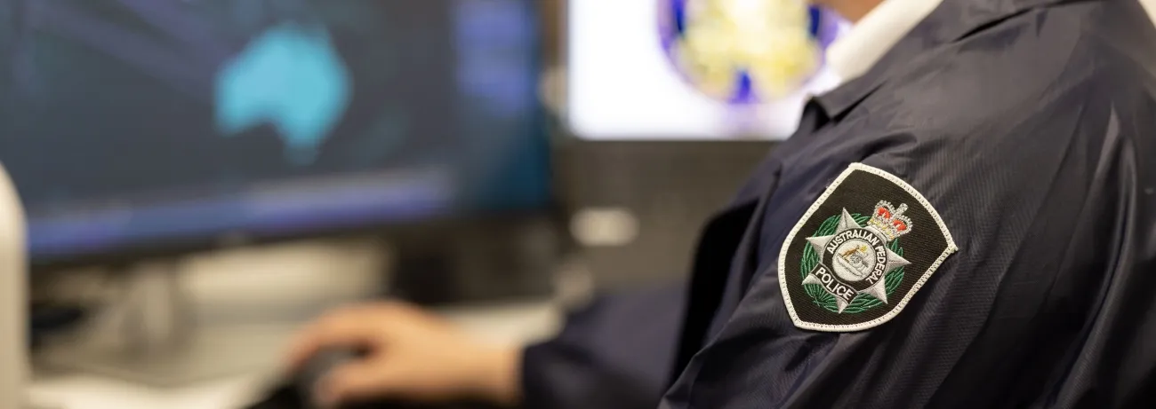 Close-up of a person in a police uniform working at a computer.
