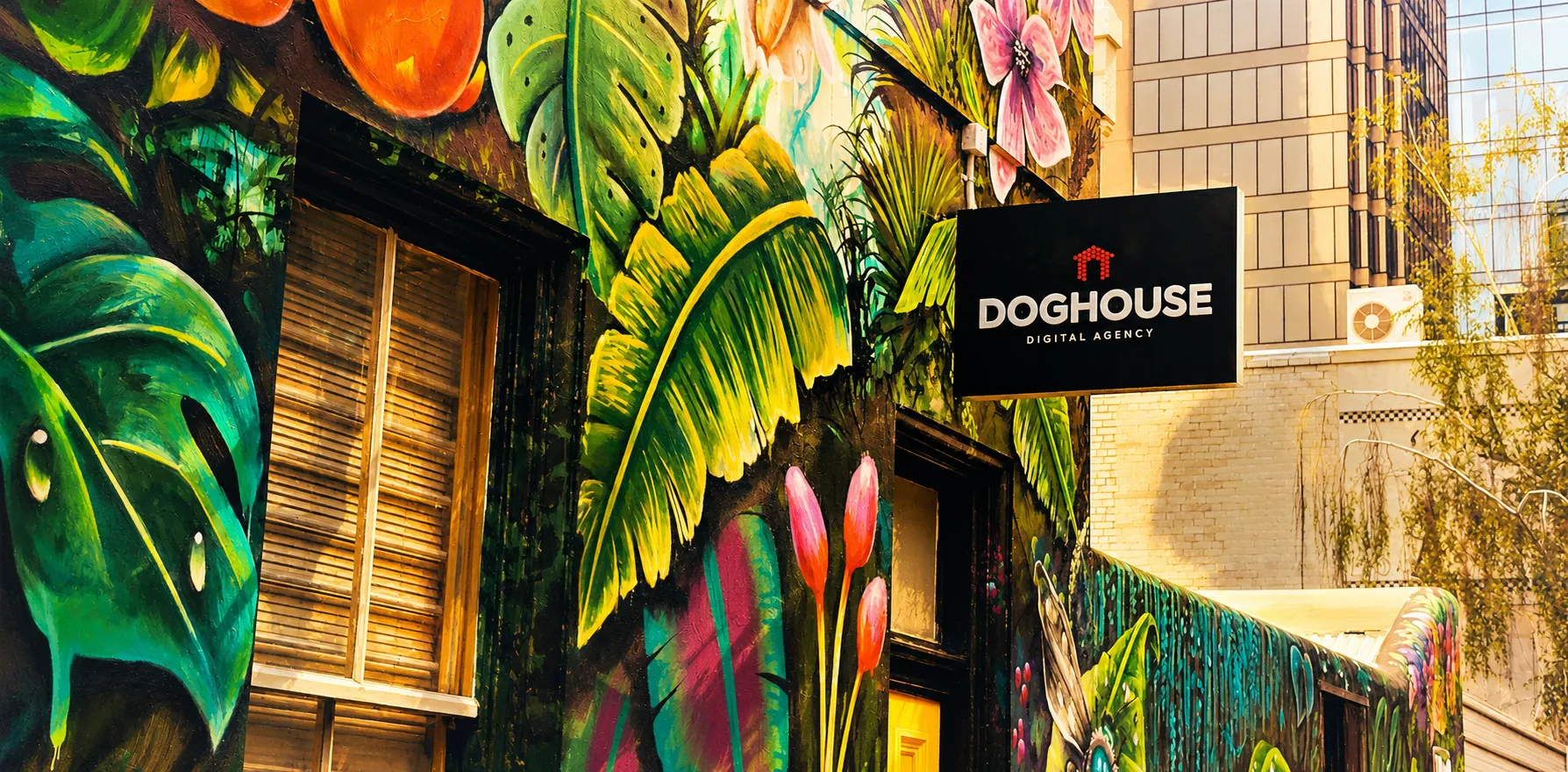 Colorful mural featuring tropical leaves and flowers beside a building with a sign for "Doghouse."