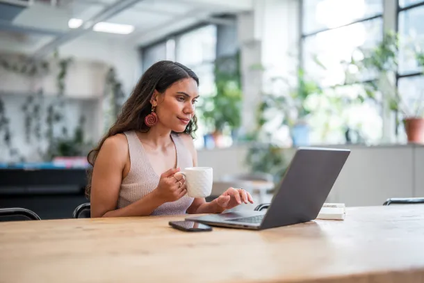 Female, relaxed having a coffee working at computer